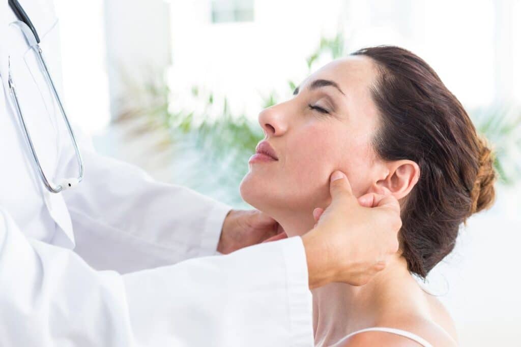 Certified plastic surgeon consulting with a patient, examining her facial structure and discussing chin filler options.