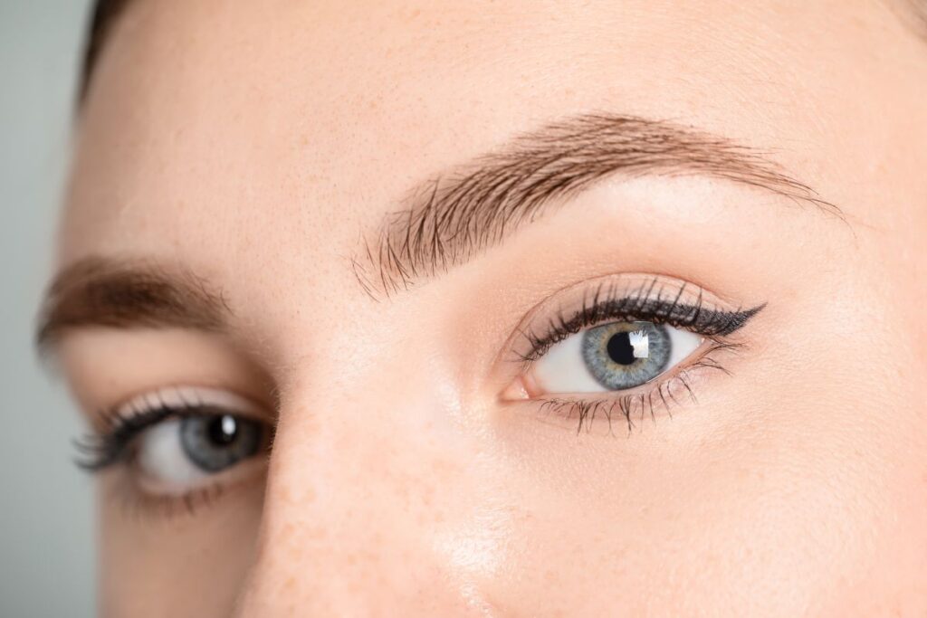 Close-up of a woman's eyes and eyebrows after a mini brow lift, showcasing smooth forehead and lifted brows for a youthful appearance.