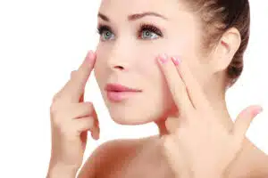 Close-up of a woman gently pressing her facial skin, questioning Botox displacement.