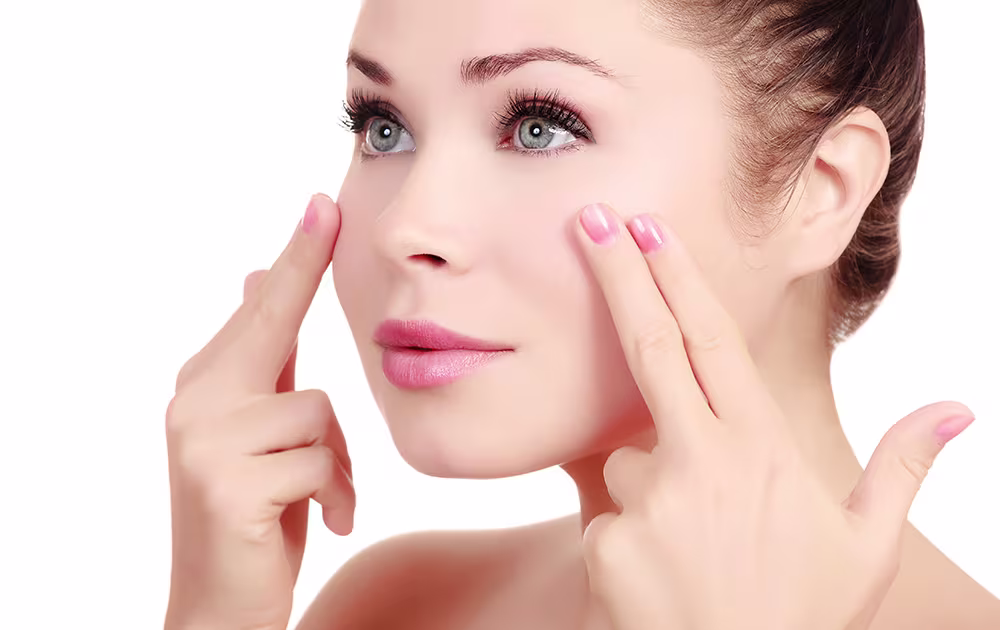 Close-up of a woman gently pressing her facial skin, questioning Botox displacement.