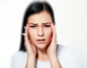 Concerned woman holding her temples, possibly experiencing double vision after Botox.