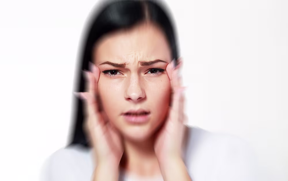 Concerned woman holding her temples, possibly experiencing double vision after Botox.