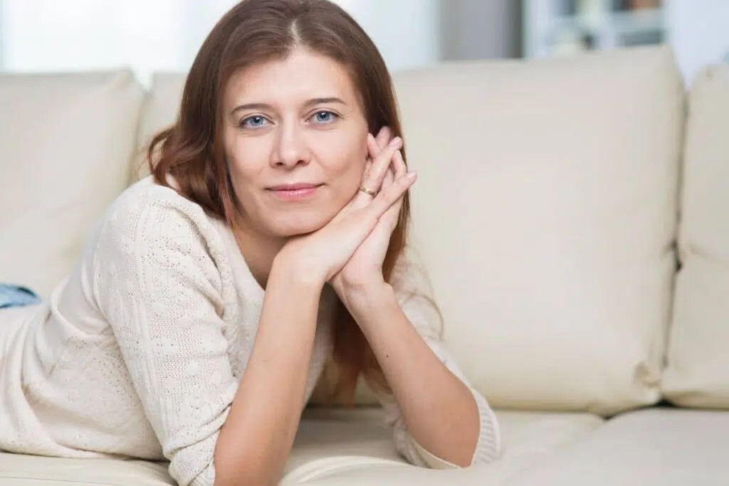 Woman resting on couch looking calm, representing ideal timing for facial rejuvenation after weight stabilization.