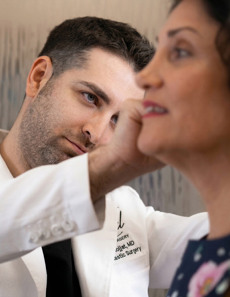 Facial plastic surgeon examining a woman’s ear during consultation in Irvine clinic, highlighting specialized facial care.